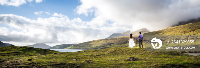 A happy couple in wedding dresses or the bride and groom holding hands and looking at the picturesqu