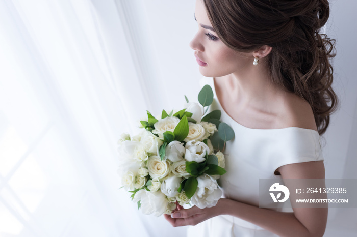 attractive bride in traditional dress holding wedding bouquet