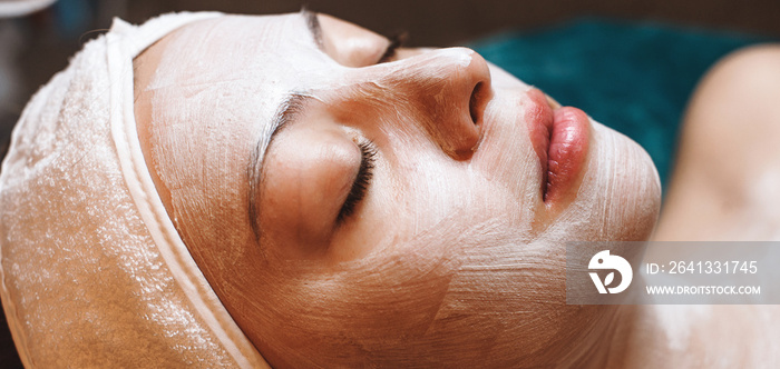 Side view portrait of a caucasian woman with closed eyes lying on the couch and having a skin care m