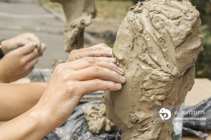 雕塑家创作了一尊半身像，并将双手粘土放在雕塑的骨架上。特写