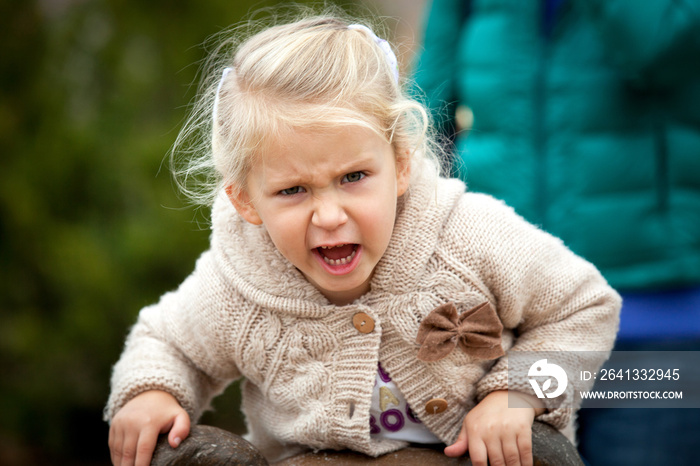 An angry little girl is very disgruntled with something being photographed