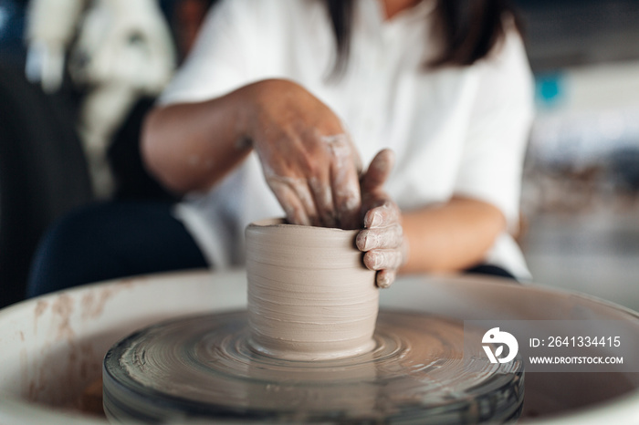 Woman sculpts an object on a potters wheel