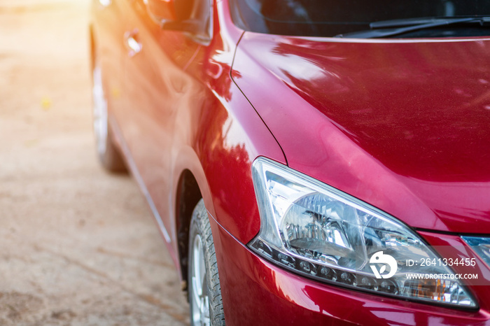 Closeup of headlight ,window of red car outdoors.