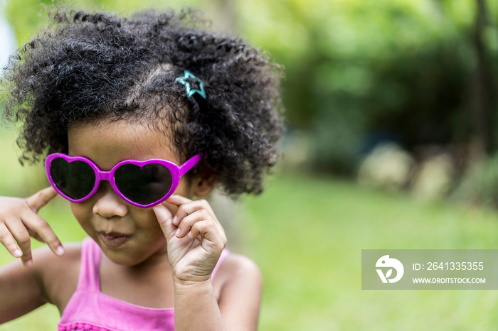 Close up shot of stylish or Happy little child girl with curly hair in sunglasses smiling on outdoor