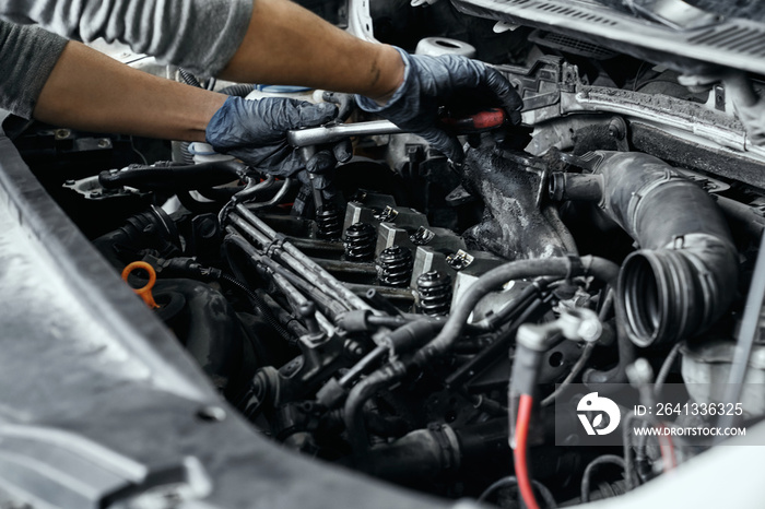 Close up of mans hands using wrench to remove spark plugs