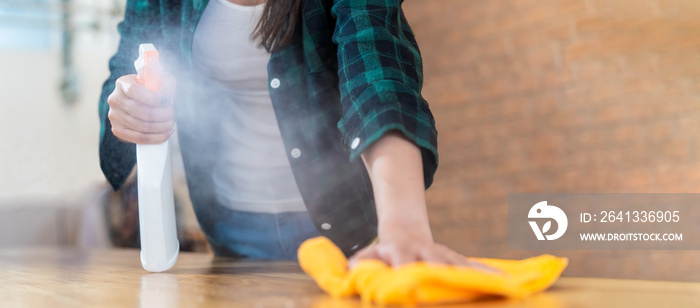 Close up view of happy woman clean home or restaurant. She wiping dust using spray and orange fabric