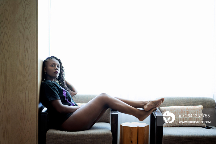 Black woman with braids relaxing in chair in front of window