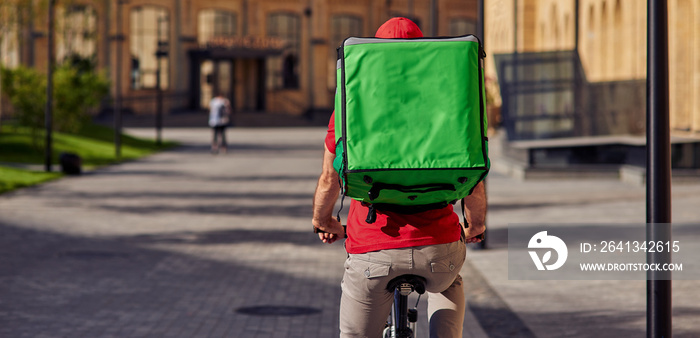 Delivery man with refrigerator bag riding away on bicycle