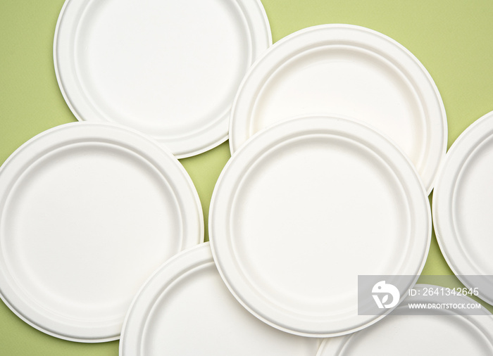 white paper disposable plates on a green background, top view.