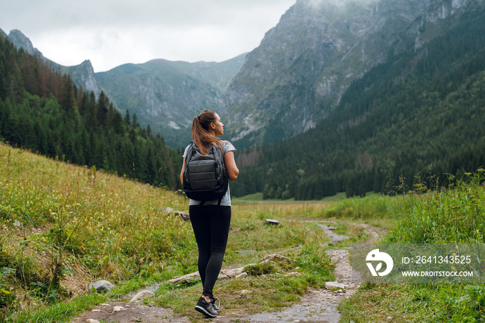 年轻的深色背包女子在塔特拉山脉的绿色小路上徒步前往瑞西的后照