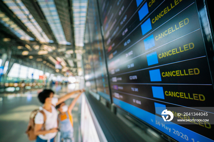 Asian female traveler looking on  flights information board in airport and it show flights cancellat