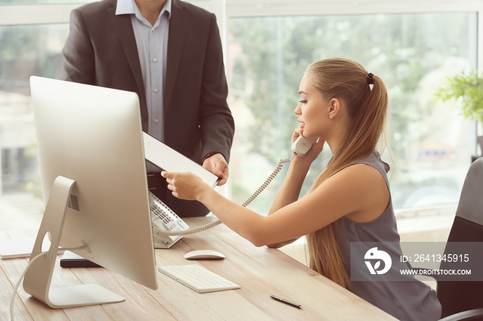 Beautiful female secretary working with colleague in office