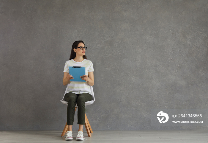 Female candidate waiting for job interview in corridor. Studio shot of unemployed young woman in gla