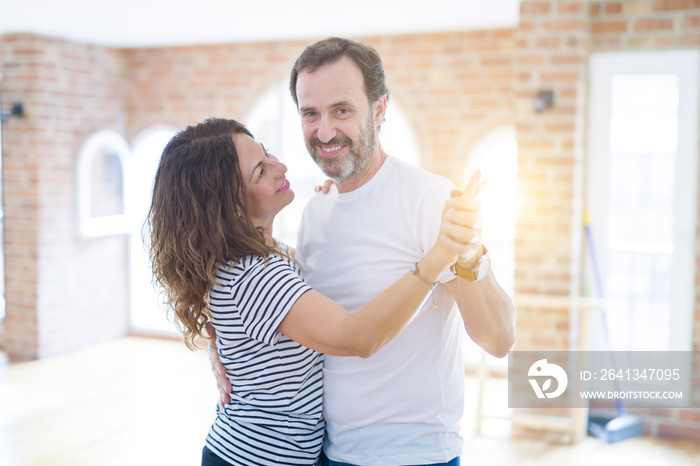 Middle age senior couple moving to a new house, dancing and smiling happy in love with apartmant