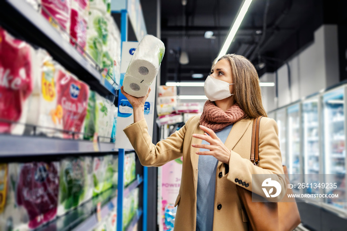 A woman with a face mask is shopping toilet paper for her home. A woman in the supermarket.