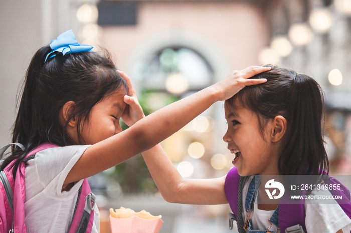 Back to school. Two cute asian child girls with school bag playing together after school in the scho