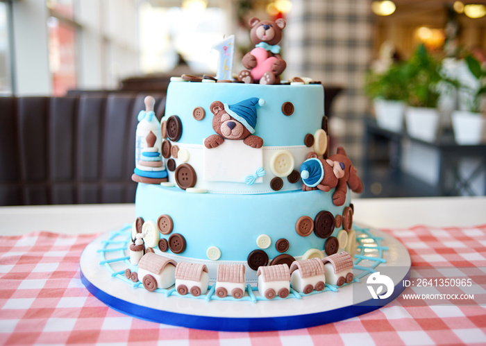 圆形多层蓝色生日蛋糕，饰有纽扣、玩具、熊、机车和一号
