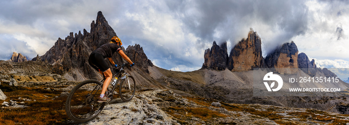 Tourist cycling in Cortina dAmpezzo, stunning rocky mountains on the background. Woman riding MTB e