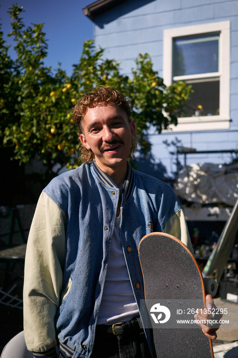 Portrait of young non-binary standing with skateboard smiling