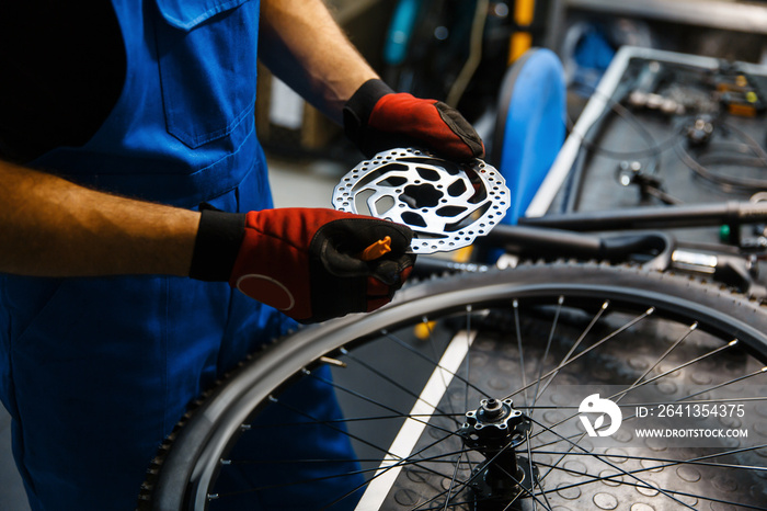 Bicycle repair in workshop, man fixing brake disk