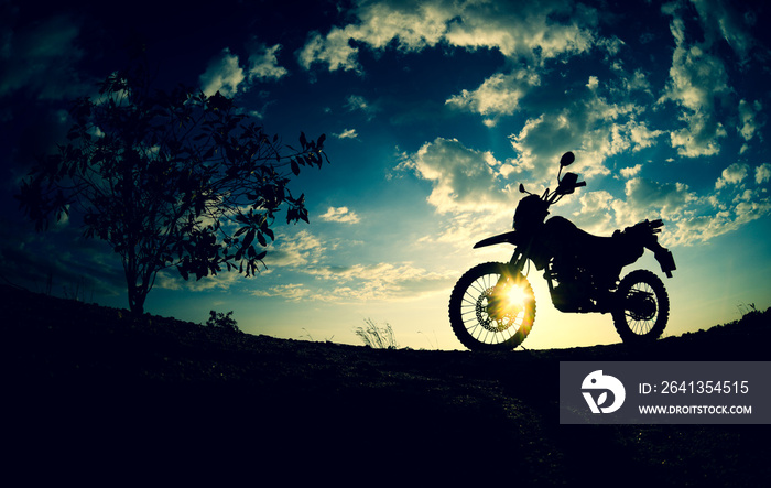 Silhouette of a motocross motorcycle parked on a mountain.