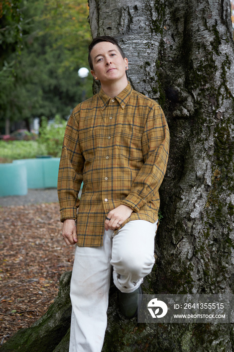 portrait of nonbinary person leaning on tree