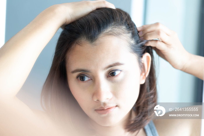 Woman looking reflection in the mirror serious hair loss problem for health care shampoo and beauty 