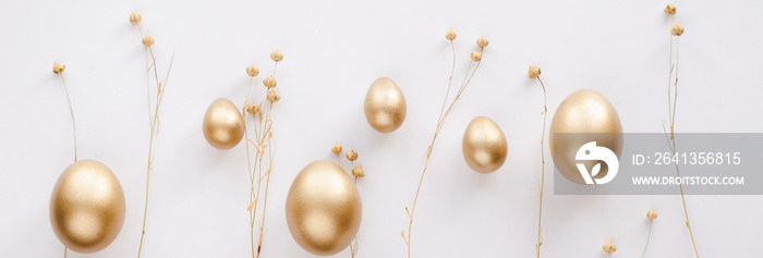 时尚的金色彩蛋复活节概念。复活节金色彩蛋配金色干亚麻亚麻束白色背景