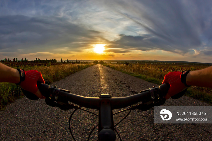 手放在方向盘上，骑着自行车在日落的路上。