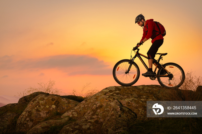 Cyclist in Red Riding Bike on the Spring Rocky Trail at Sunset. Extreme Sport and Enduro Biking Conc