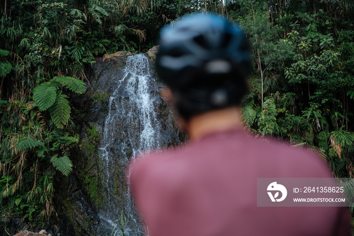 A young female cyclist is looking at the waterfalls.