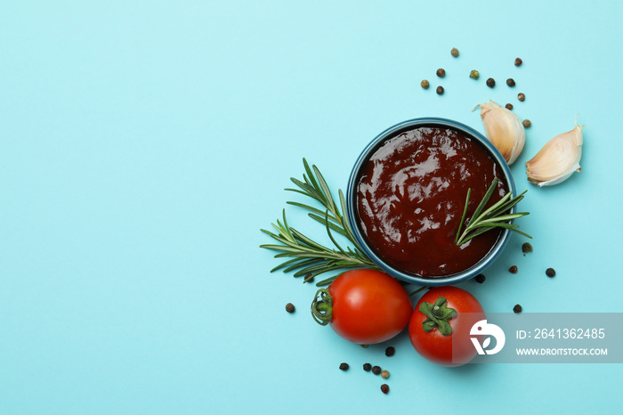 Bowl of barbecue sauce and spices on blue background