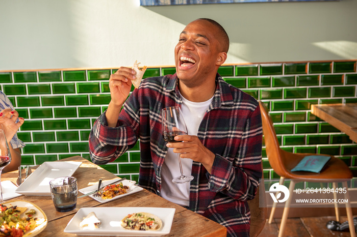 UK, London, Man enjoying red wine and Mexican food at restaurant table