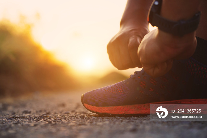 Close-up sportman tying sneakers with sunlight at sunset background. Runner and exercise concept.