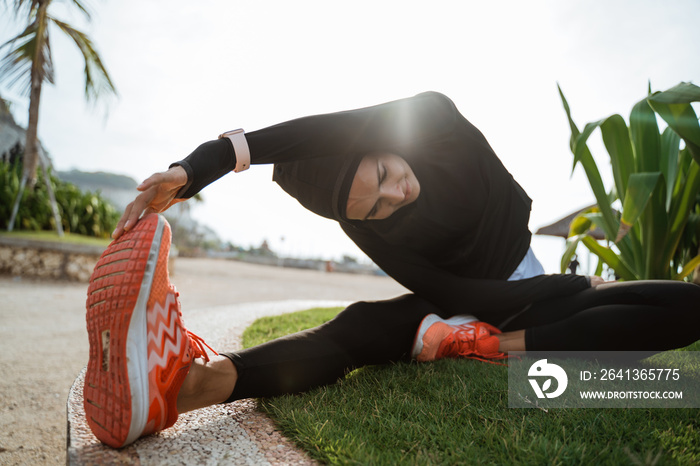 woman with muslim sport wear stretching. sporty female using head scarf exercising