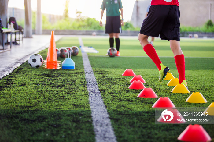 Soccer player Jogging and jump between cone markers on green artificial turf for soccer training.