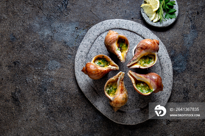 Chilean giant snails with butter, garlic and herbs on gray stone  plate. escargot from pacific ocean