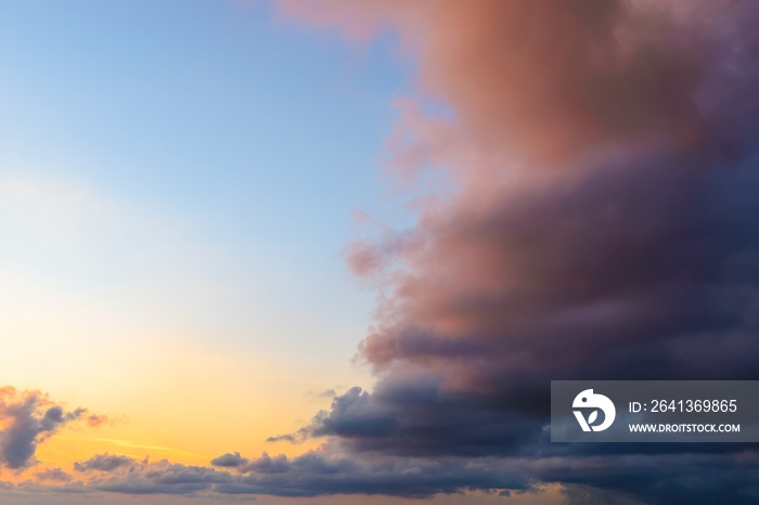 olden azure evening sky is half covered by a dark storm cloud, dyed reddish by the setting sun. Calm