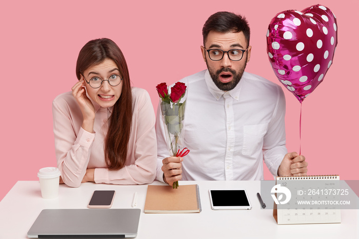 Surprised bearded man holds valentine and bouquet of roses, flirts with secretary, have office roman