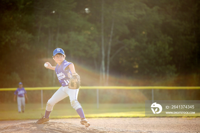 Little league player (8-9) pitching from mound