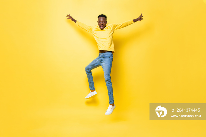 Young cheerful energetic African man jumping with outstretched hands isolated on yellow studio backg