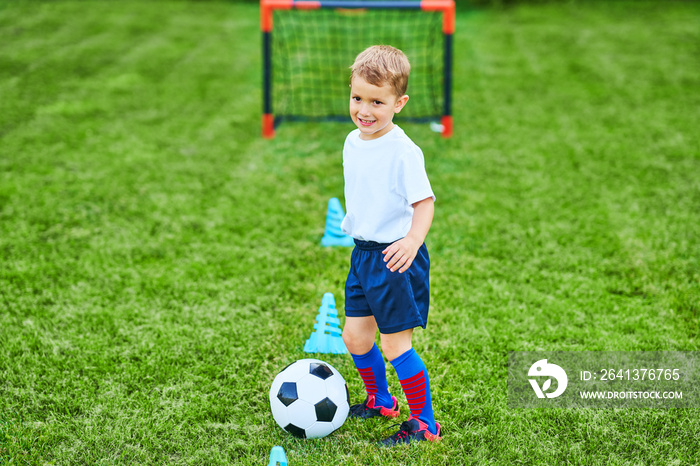 Little Boy practising soccer outdoors