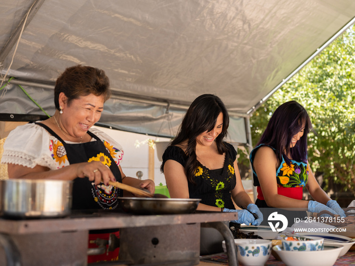 Horizontal image of an Indigenous family laughing while preparing Indigenous foods