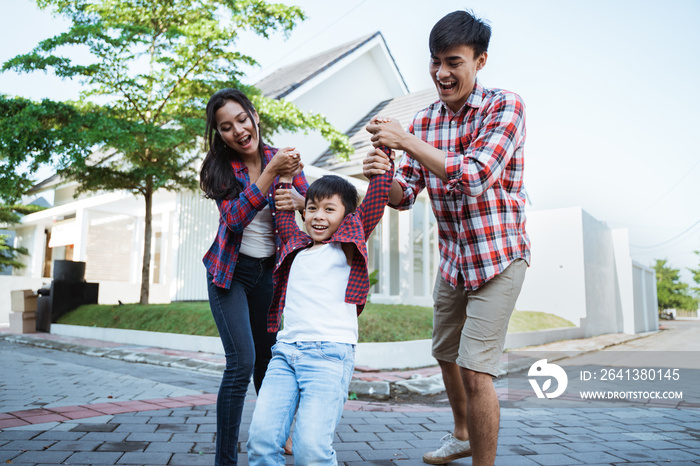 new home concept. parent with kid enjoying playing together in front of their new house