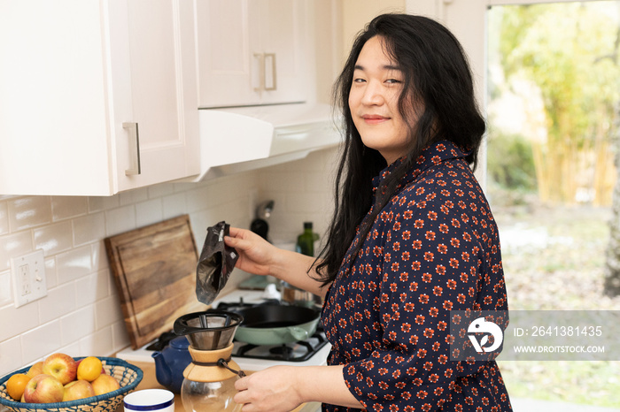 亚洲跨性别女性在厨房准备咖啡。