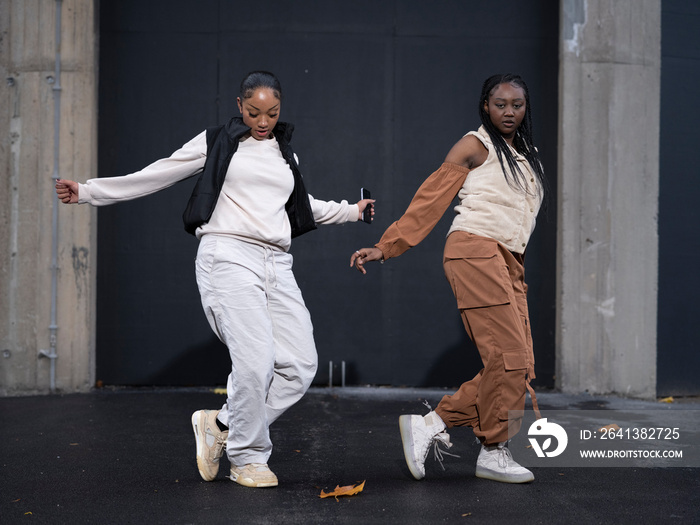 Two teenage girls dancing in city