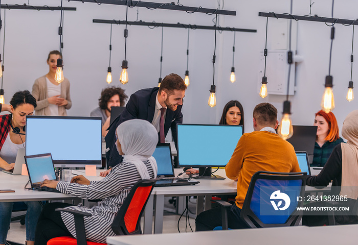 Multi-ethnic coworkers sitting at desks and working on computers in a modern office room