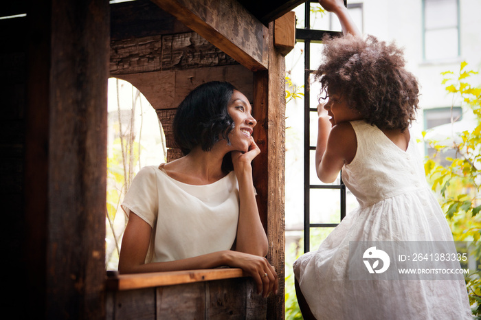 Woman face to face with daughter (8-9) in tree house