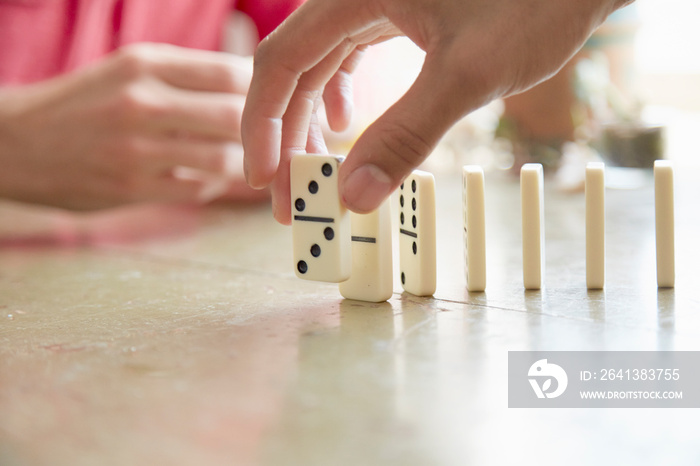 Cropped view of mans hand placing domino on edge