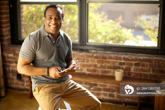 Man posing with charismatic smile holding digital tablet